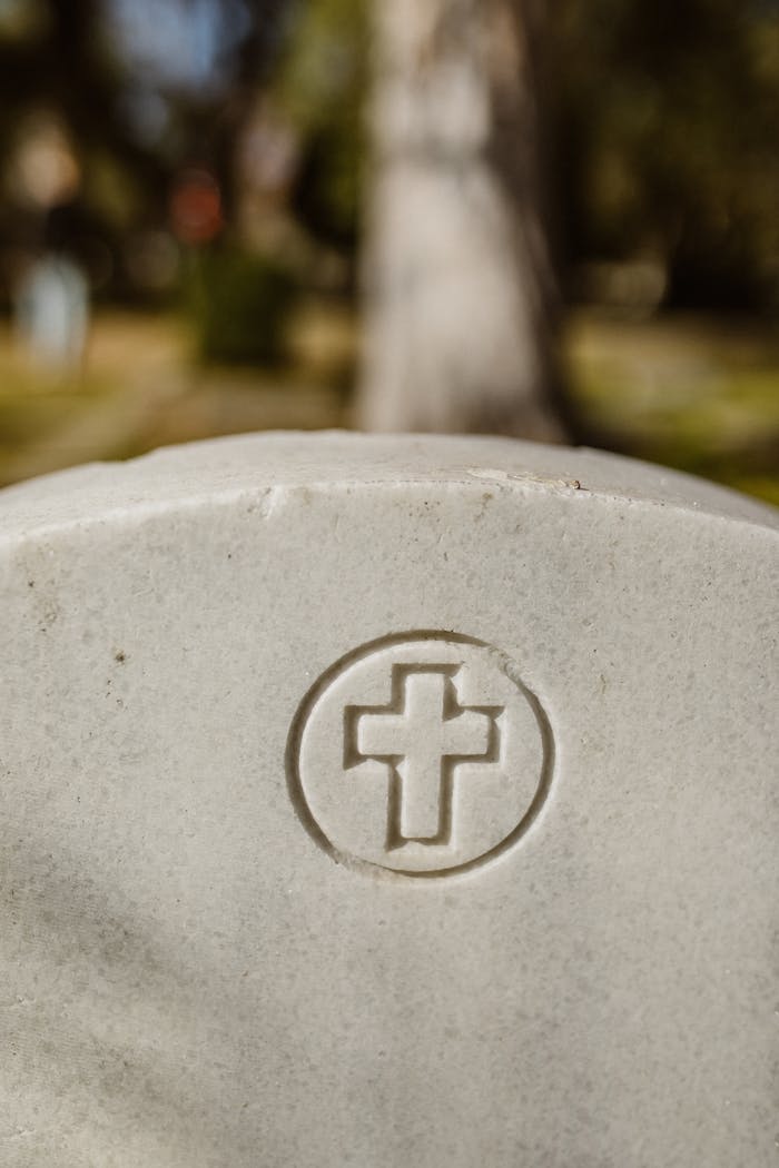 A detailed view of a gravestone featuring a cross engraving in an outdoor cemetery setting.