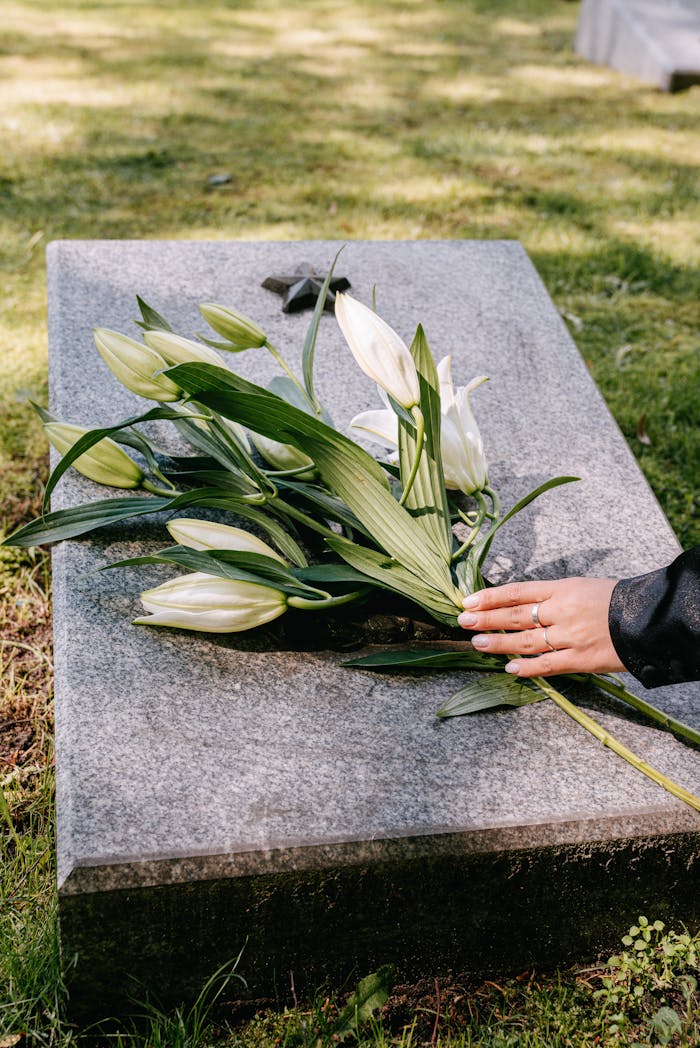 Services White lilies on a gravestone symbolize remembrance in an outdoor cemetery setting.